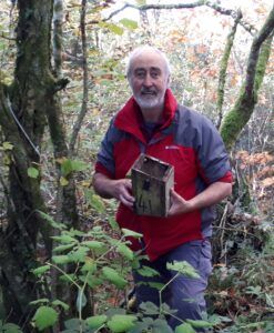 Dave Fowler, Dormouse Monitor, holding a nest box in a dense woodland